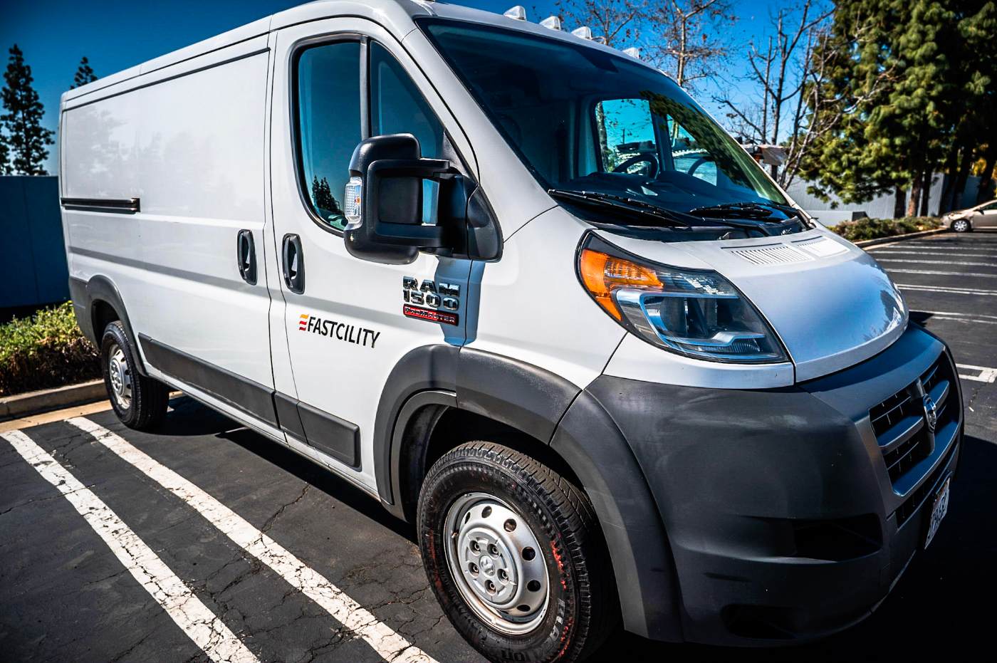 A white Fastcility service van parked outside, branded with the Fastcility logo on the driver-side panel.